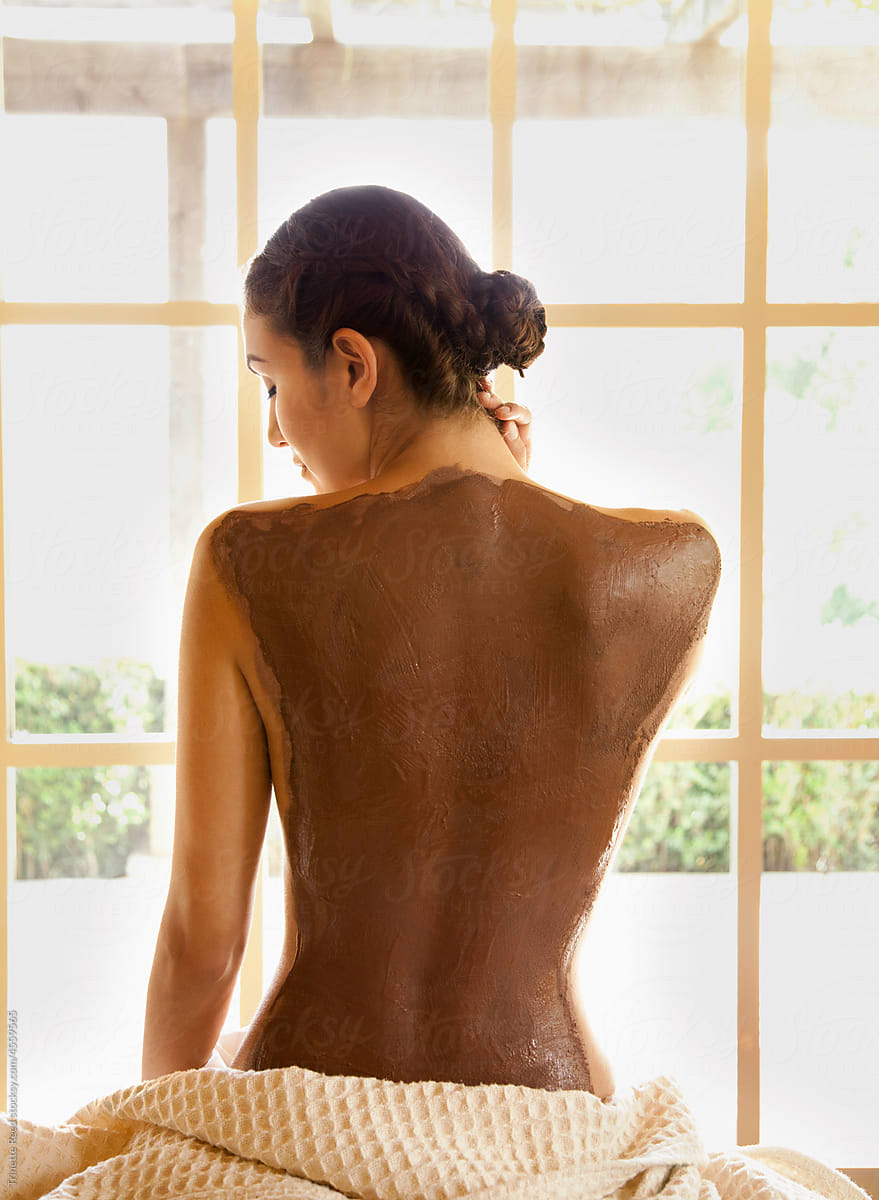 Woman relaxing at spa with skincare mud treatment on her back