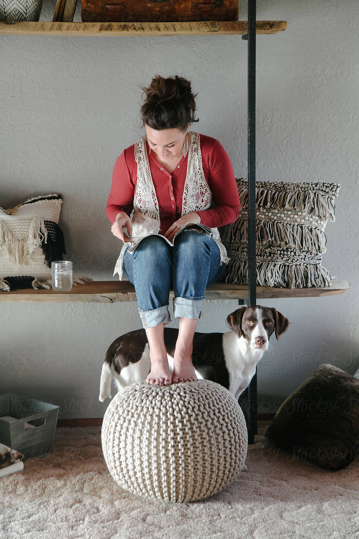 dog stands near woman leisurely reading magazine at home