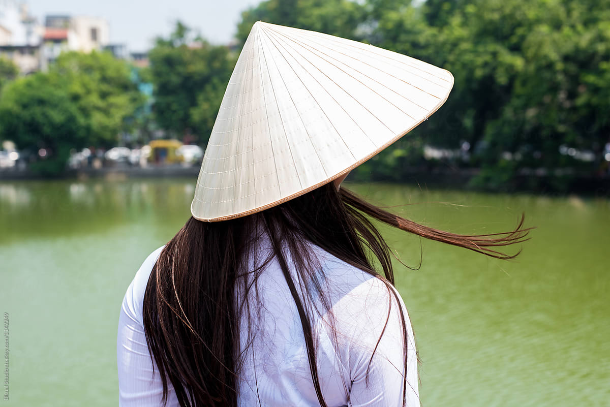 Female in Vietnamese hat near lake
