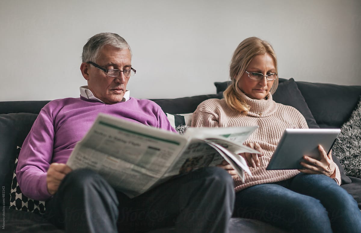 Woman Browsing Online and Man Reading Newspaper