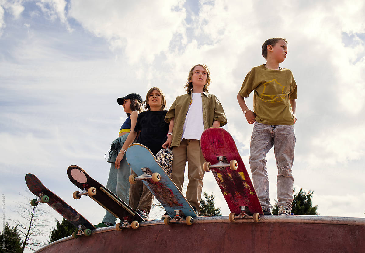 Four young skaters standing at the edge of the bowl
