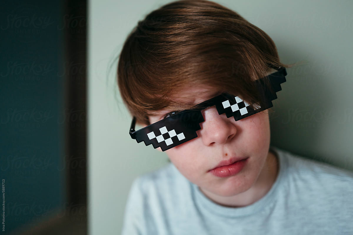 Sad young boy in pixel sunglasses.