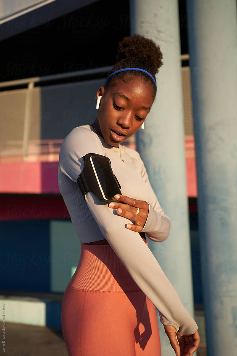 Fit black lady checking fitness tracker on smartphone