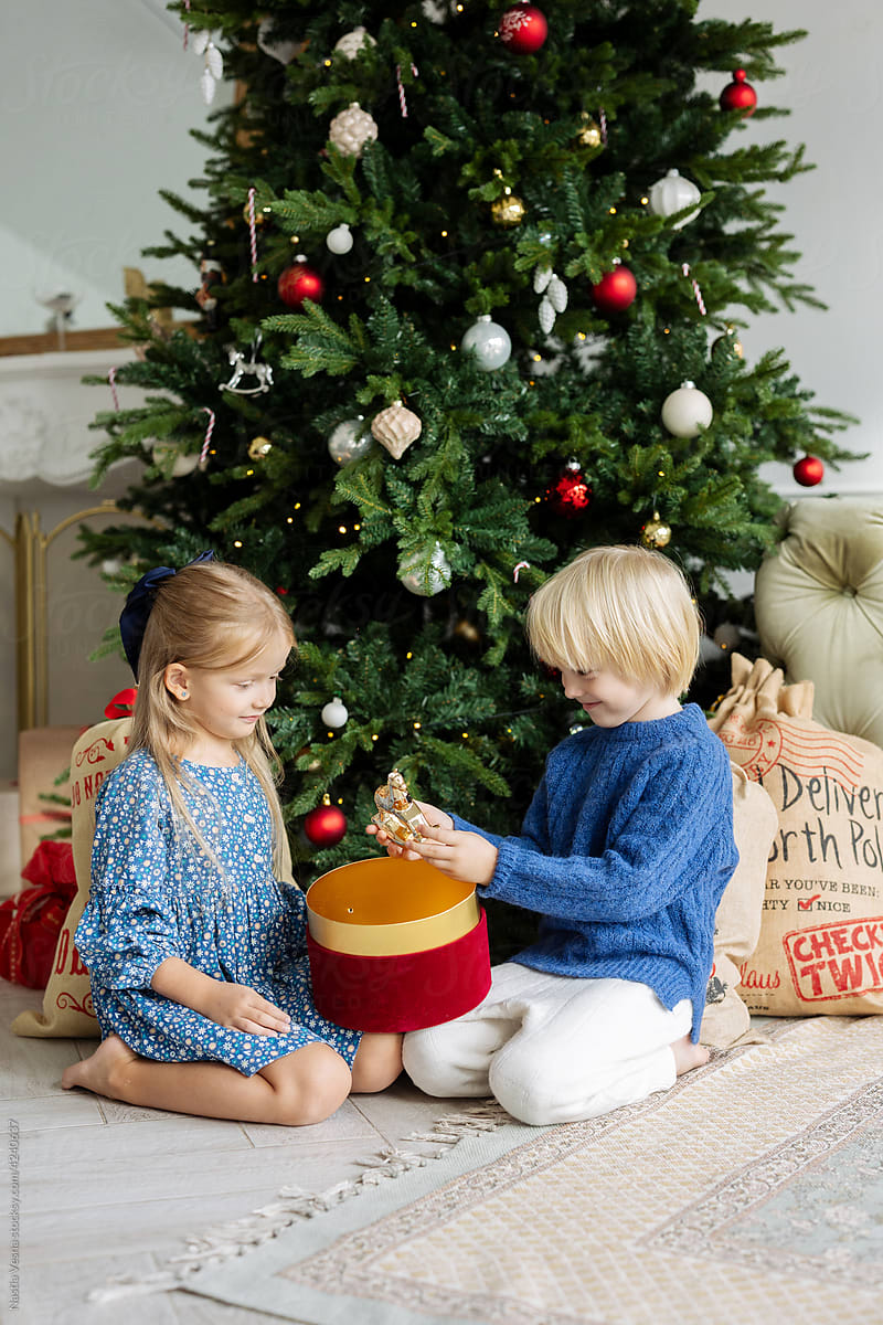 Children near the Christmas tree unpack gifts