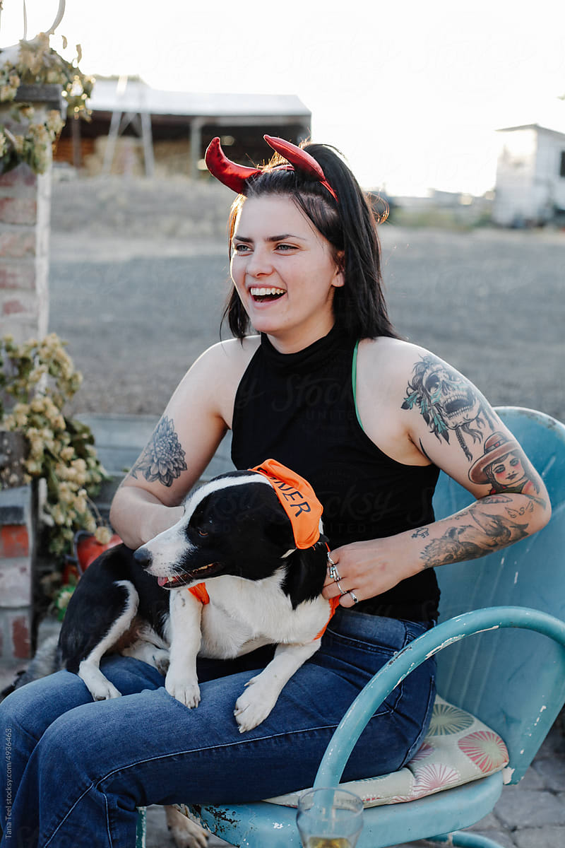 smiling woman in costume holds costumed dog for Halloween
