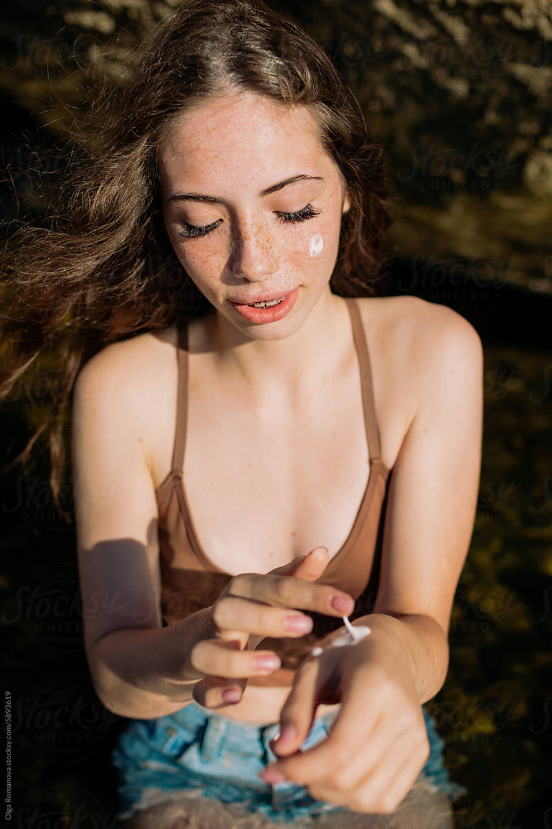 Summer portrait of a teenage girl with freckles using sunscreen