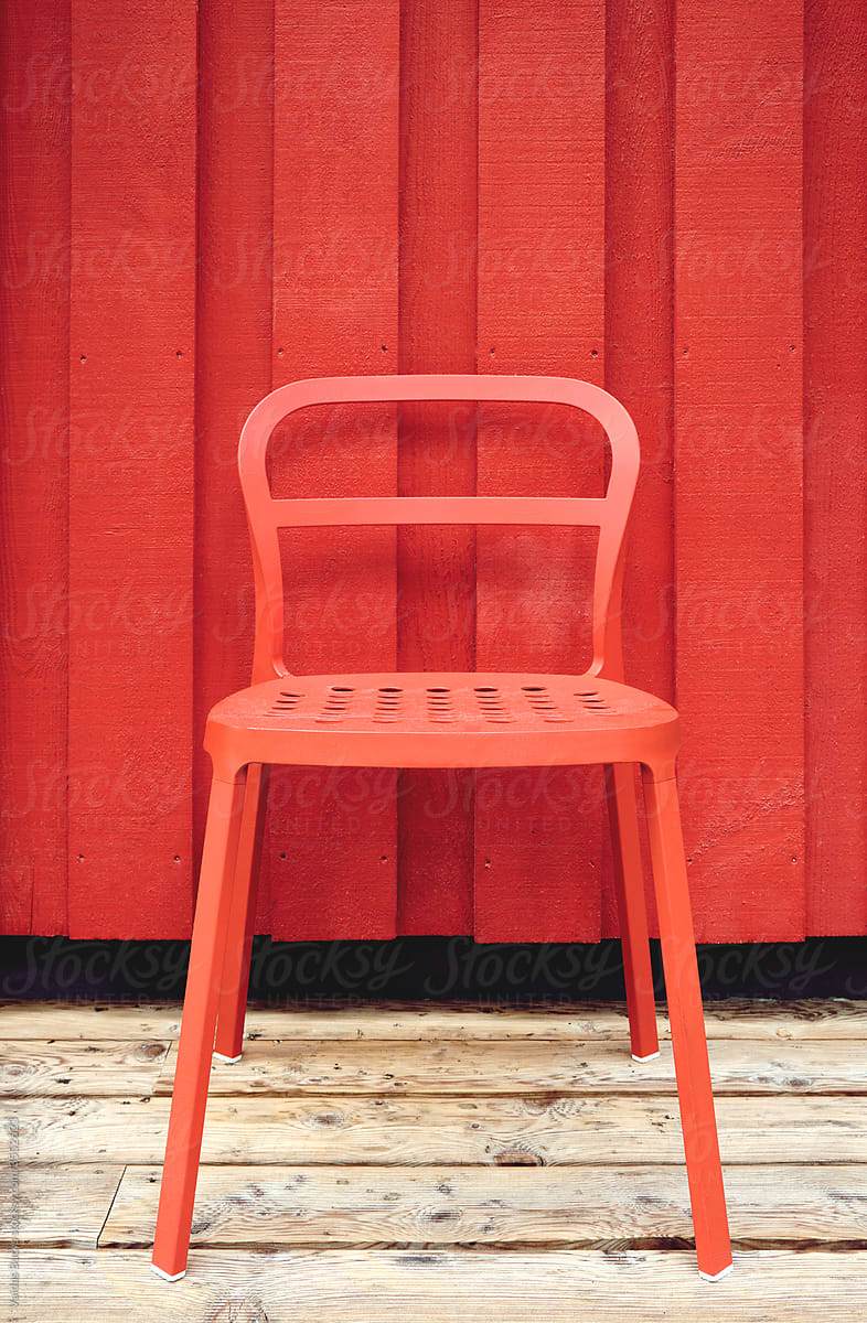Red chair standing against red wooden wall