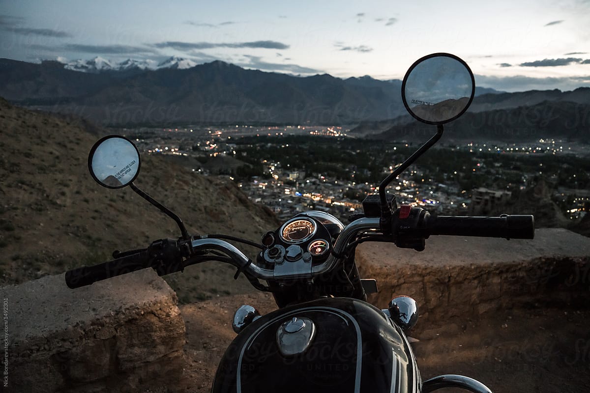 Motorcycle with headlights on, surrounded by desert town and mountains
