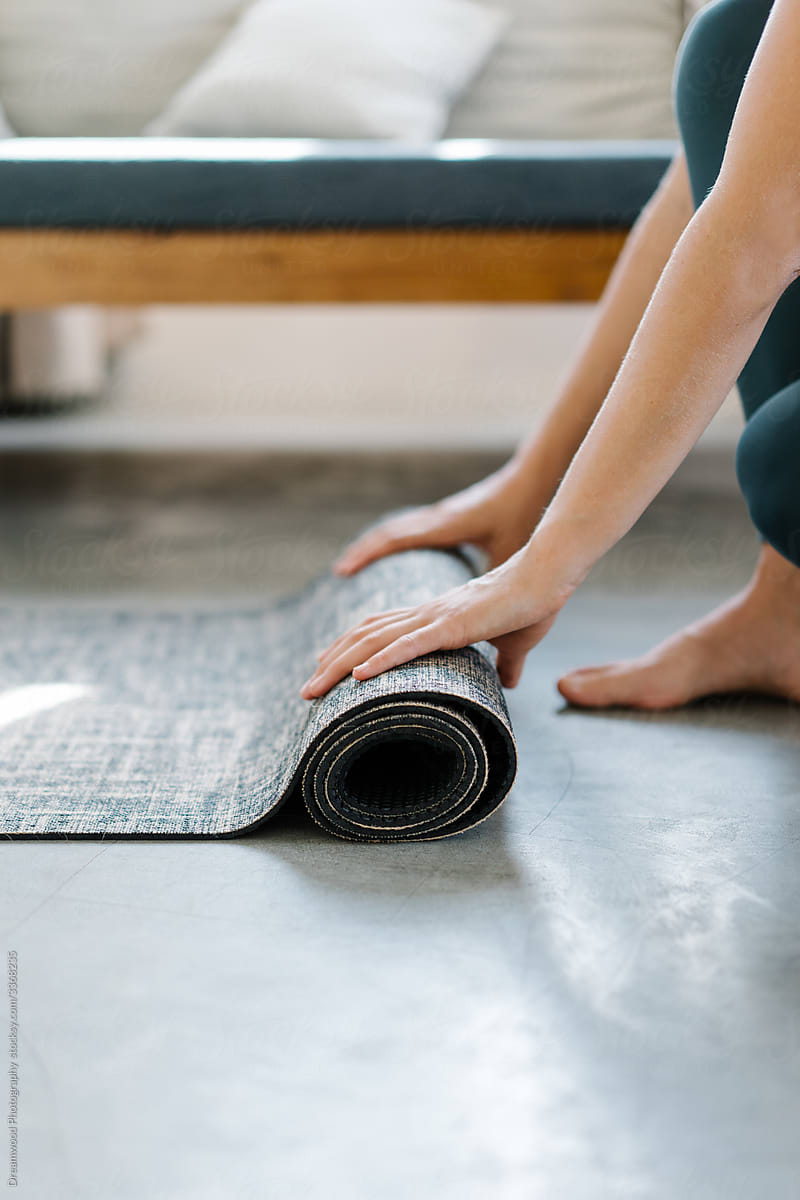 Crop woman rolling yoga mat