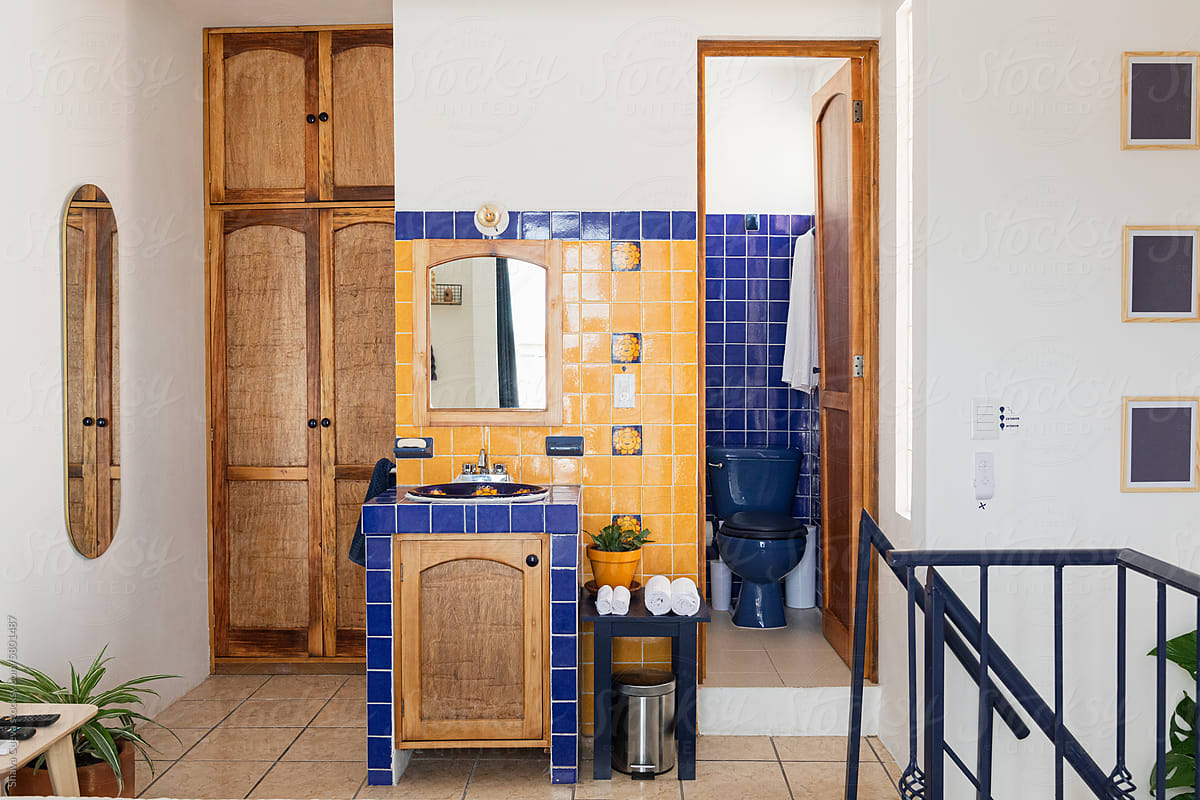 A sink and a mirror surrounded with blue and yellow tiles in a room