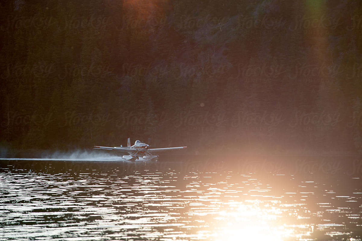 A forest fire fighting floatplane landing on a lake to fill it\'s tanks at sunset
