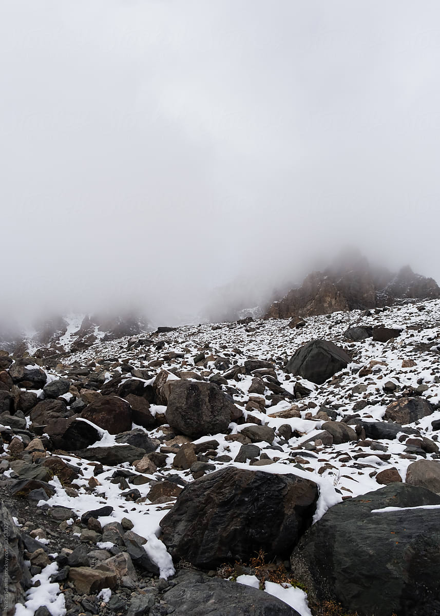 foggy mountains landscape, snowy mountains with huge stones