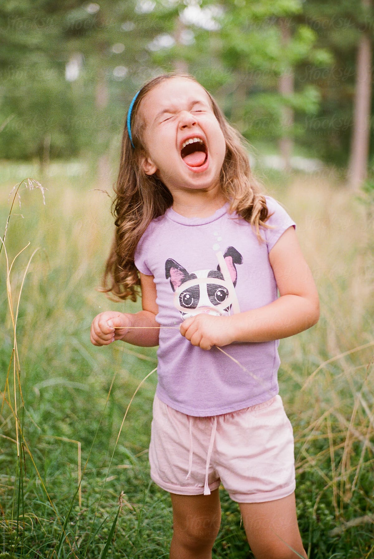 Cute Young Girl Making A Funny Face In A Field By Jakob Lagerstedt