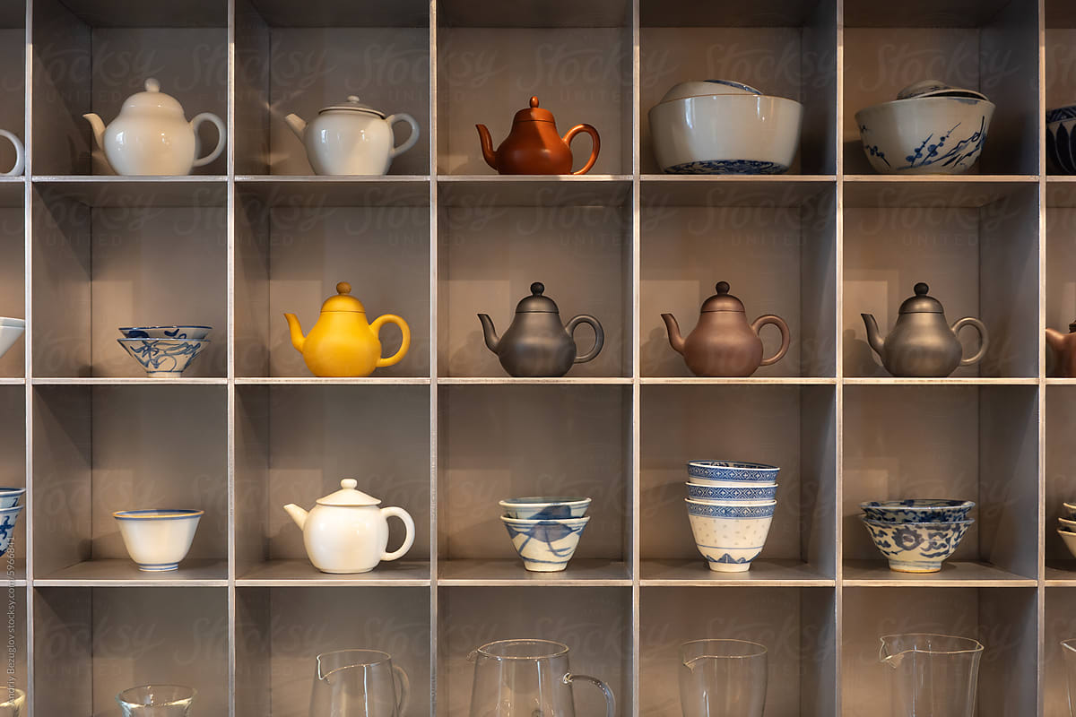 Ceramic tea pots with bowls and jugs on shelf
