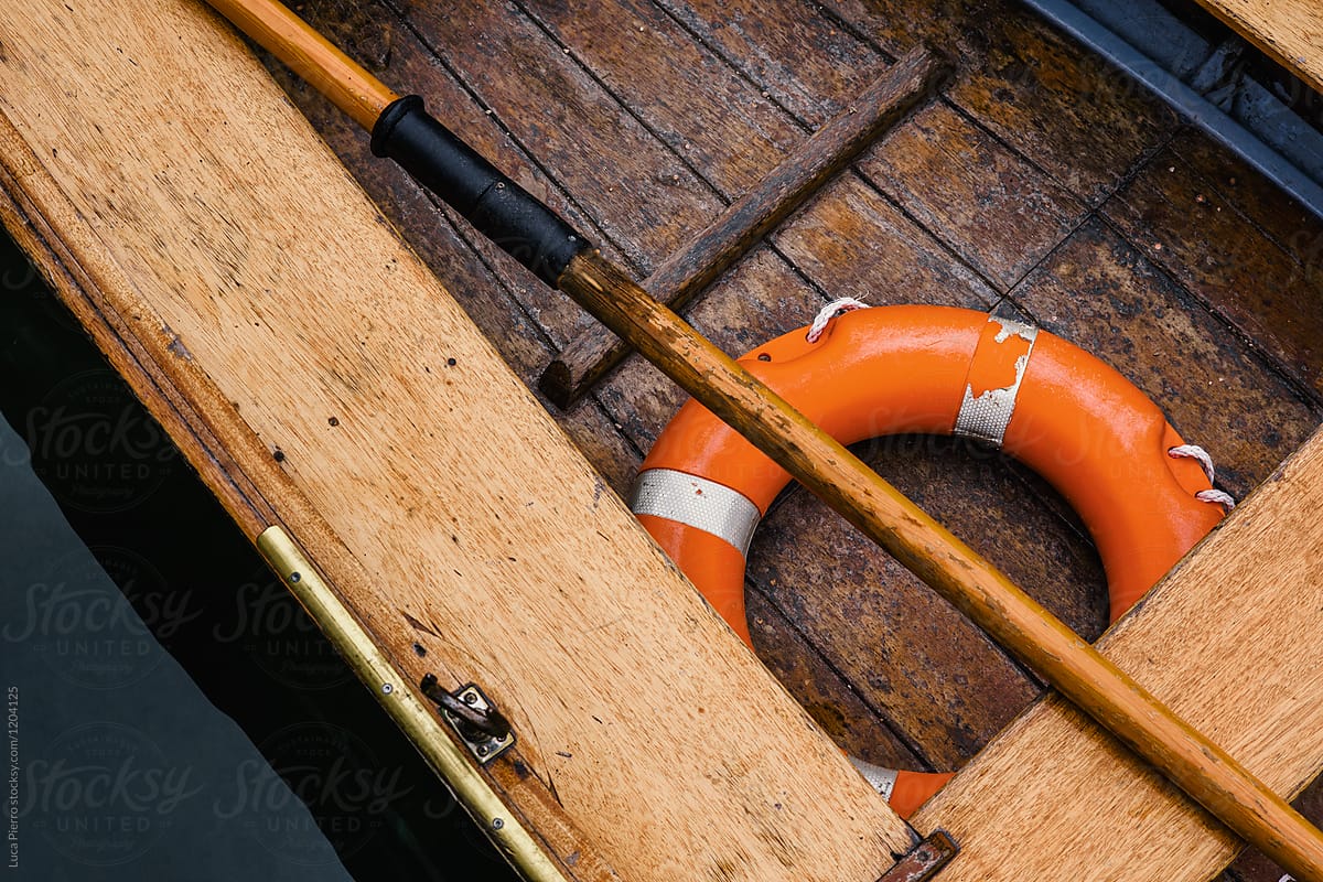 Closeup of buoy and oar in a wooden boat in lake