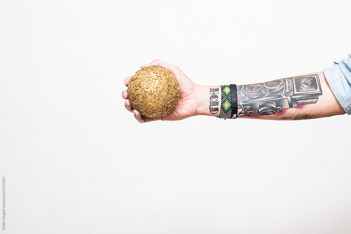 Man\'s arm with golden Christmas ball.