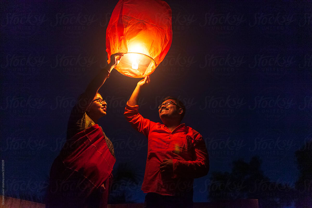 Middle aged couple holding Sky Lantern To The Sky At Twilight