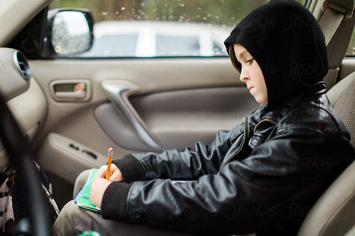 Boy sitting in car doing homework.