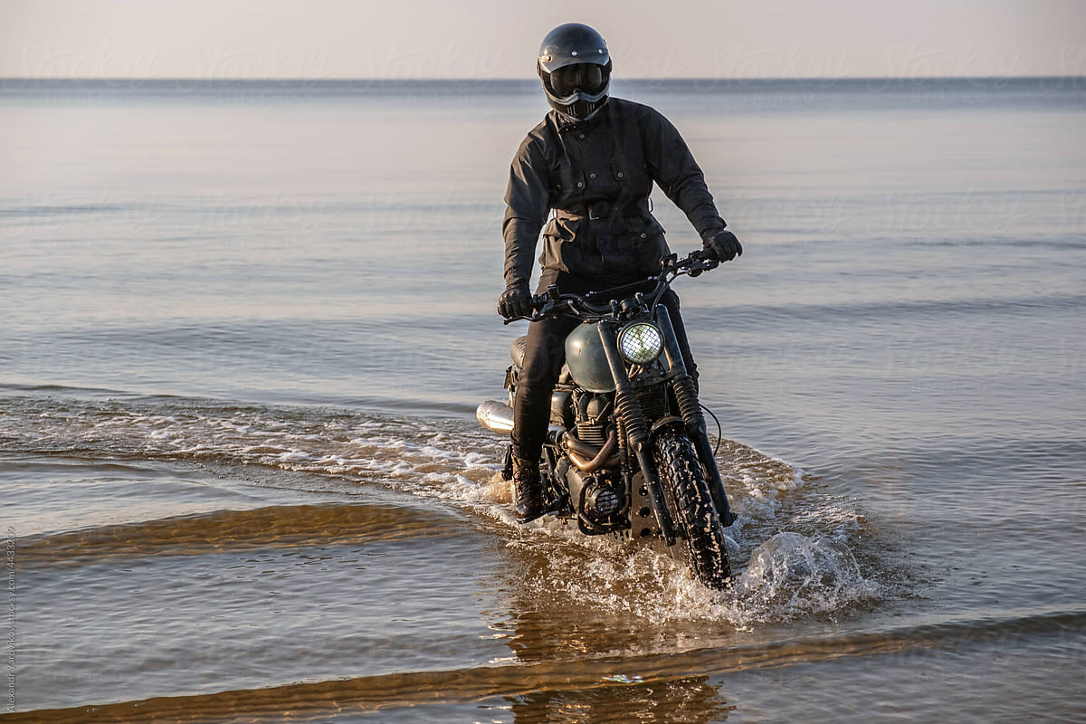 A rider on a motorcycle rides out of the water