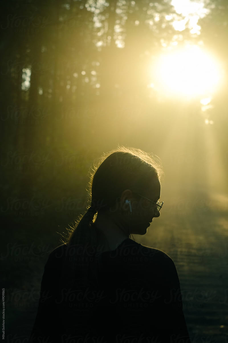 A girl walks along a forest road and listens to music