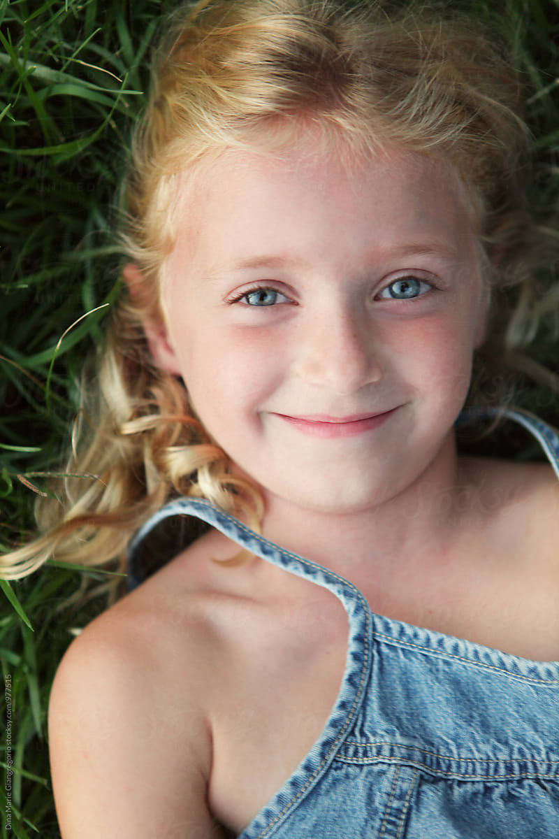 Content Little Blonde Girl Laying In Grass Smiling By Dina Marie