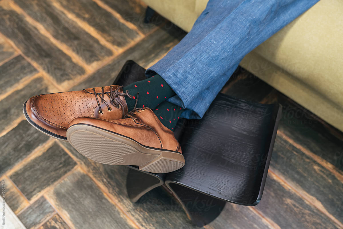 men\'s brown shoes on feet clothed into green socks