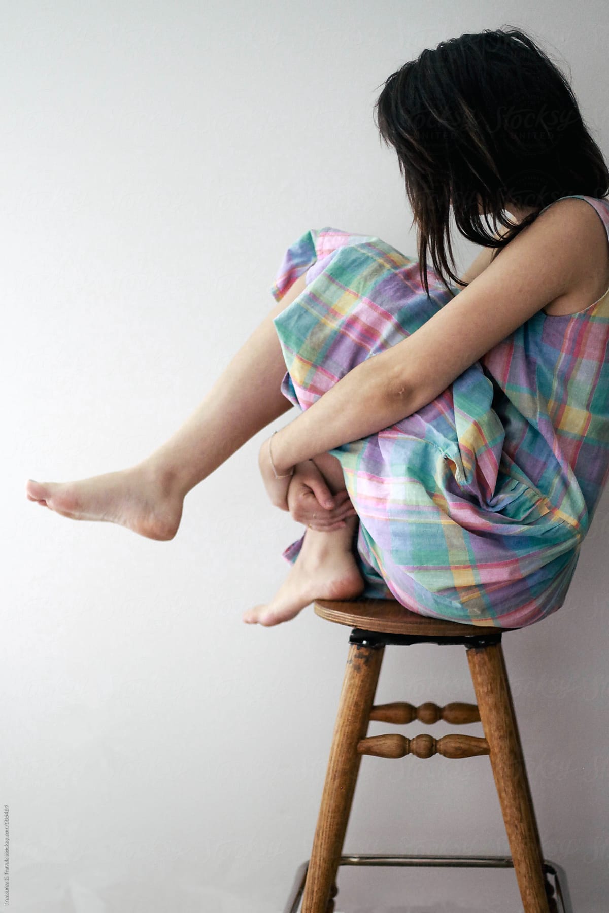 Young brunette woman sitting on stool indoors
