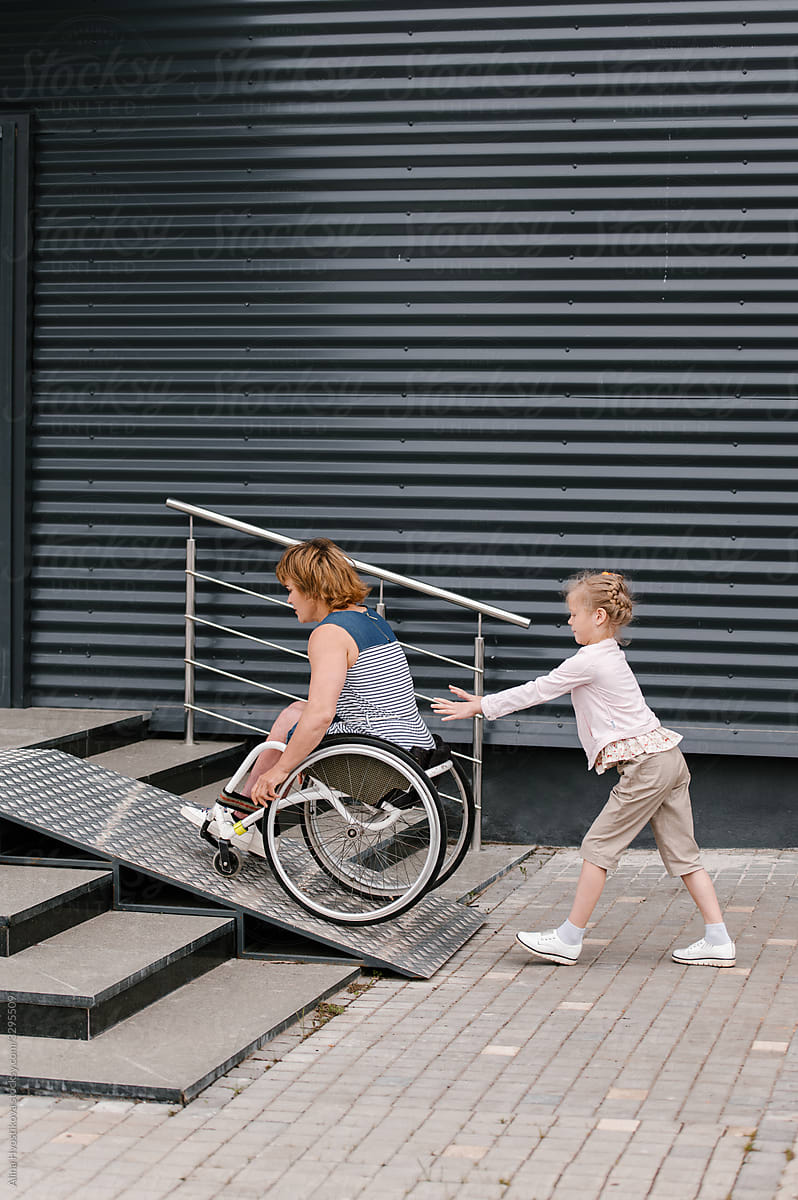 Daughter pushing mother on wheelchair on ramp