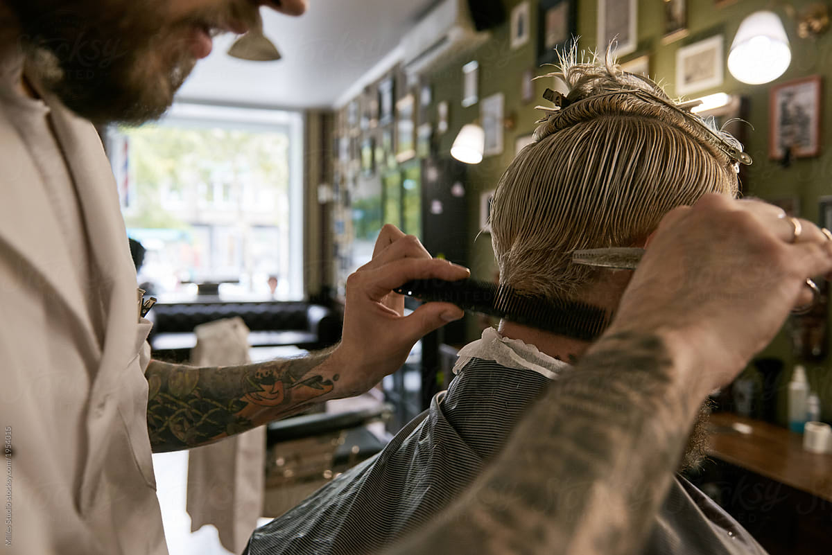 Confident hairstylist cutting client hair