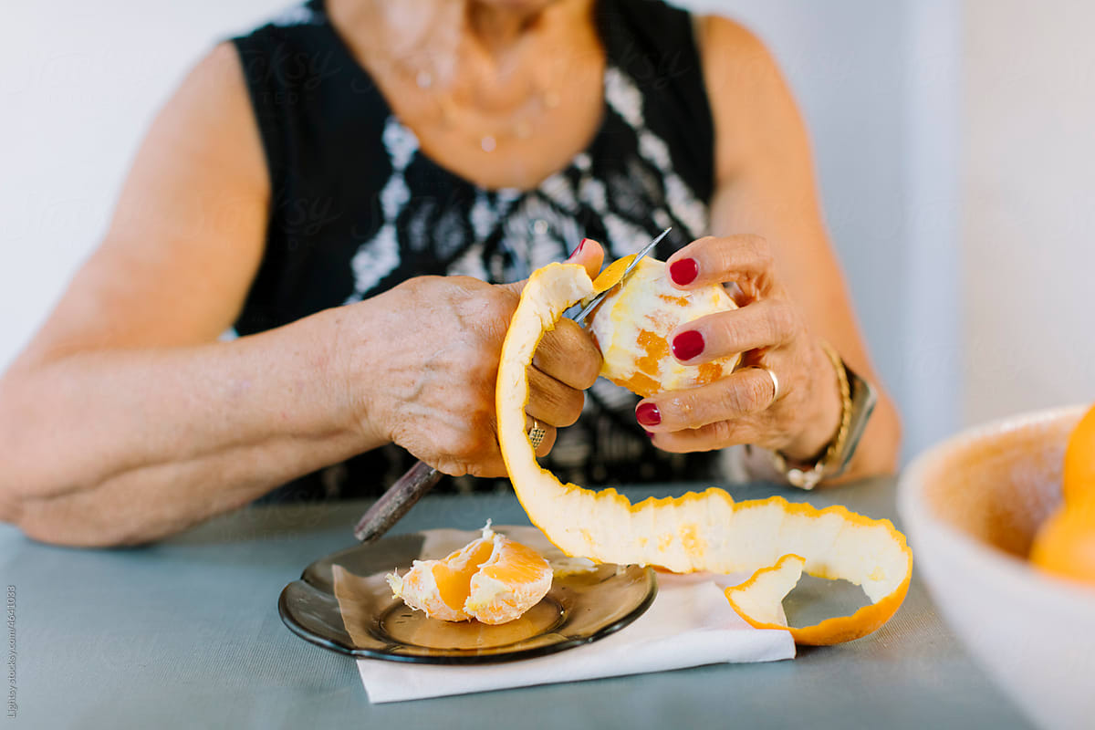 Elder woman peeling an orange