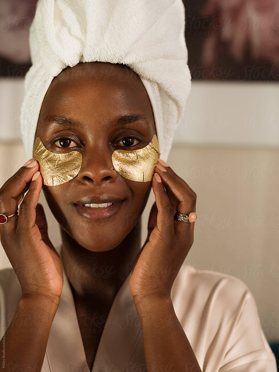 Portrait of black woman touching under eye mask