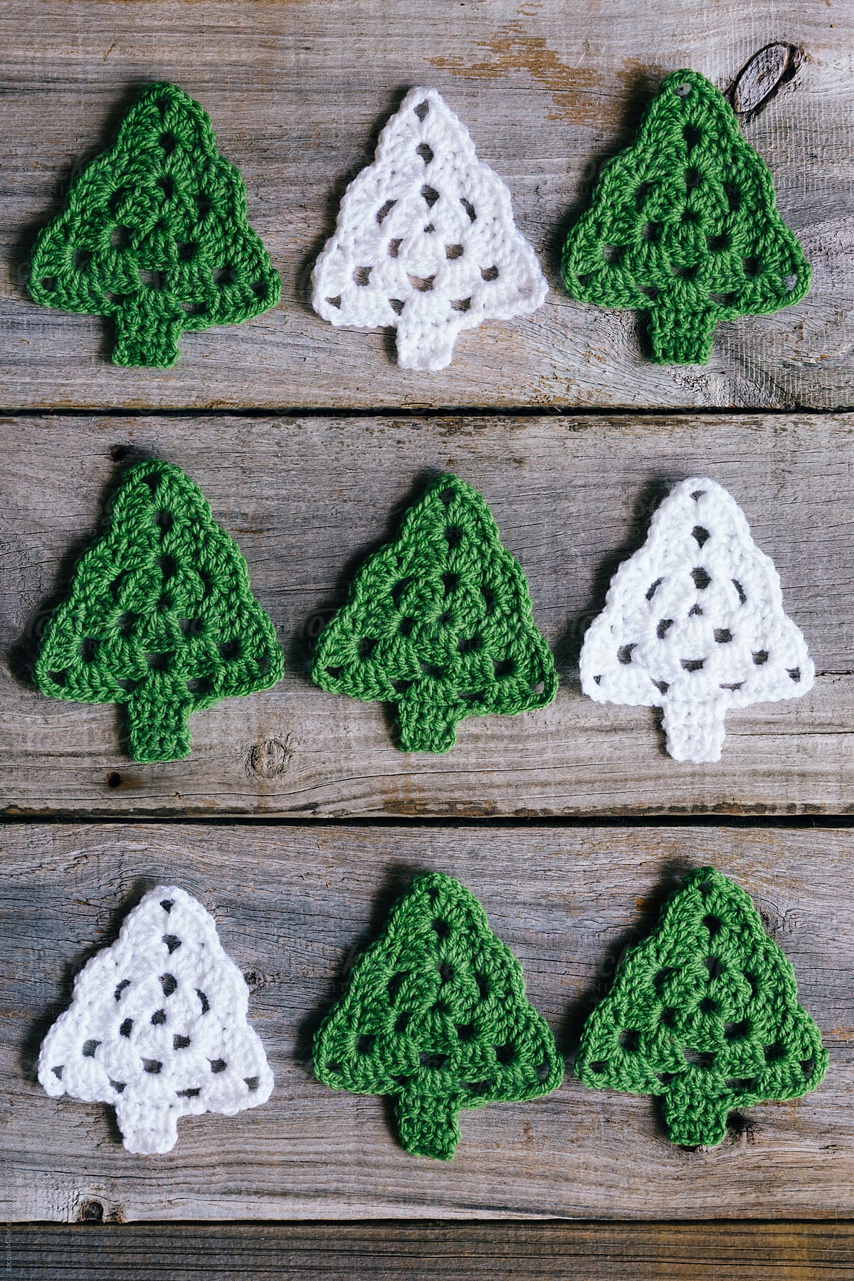 Green and White Crocheted Christmas Trees on rustic wood background - vertical