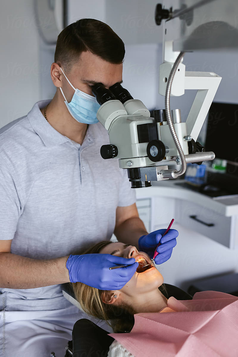 Orthodontist watching through microscope on oral cavity
