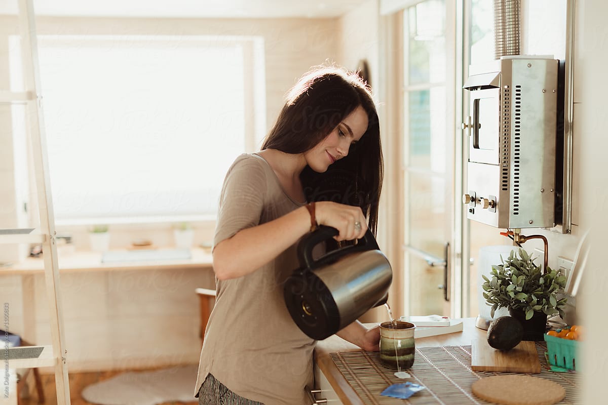 Woman making tea in the morning in her tiny home.