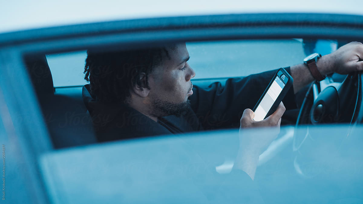 African-American Man Sitting In The Car And Using Phone