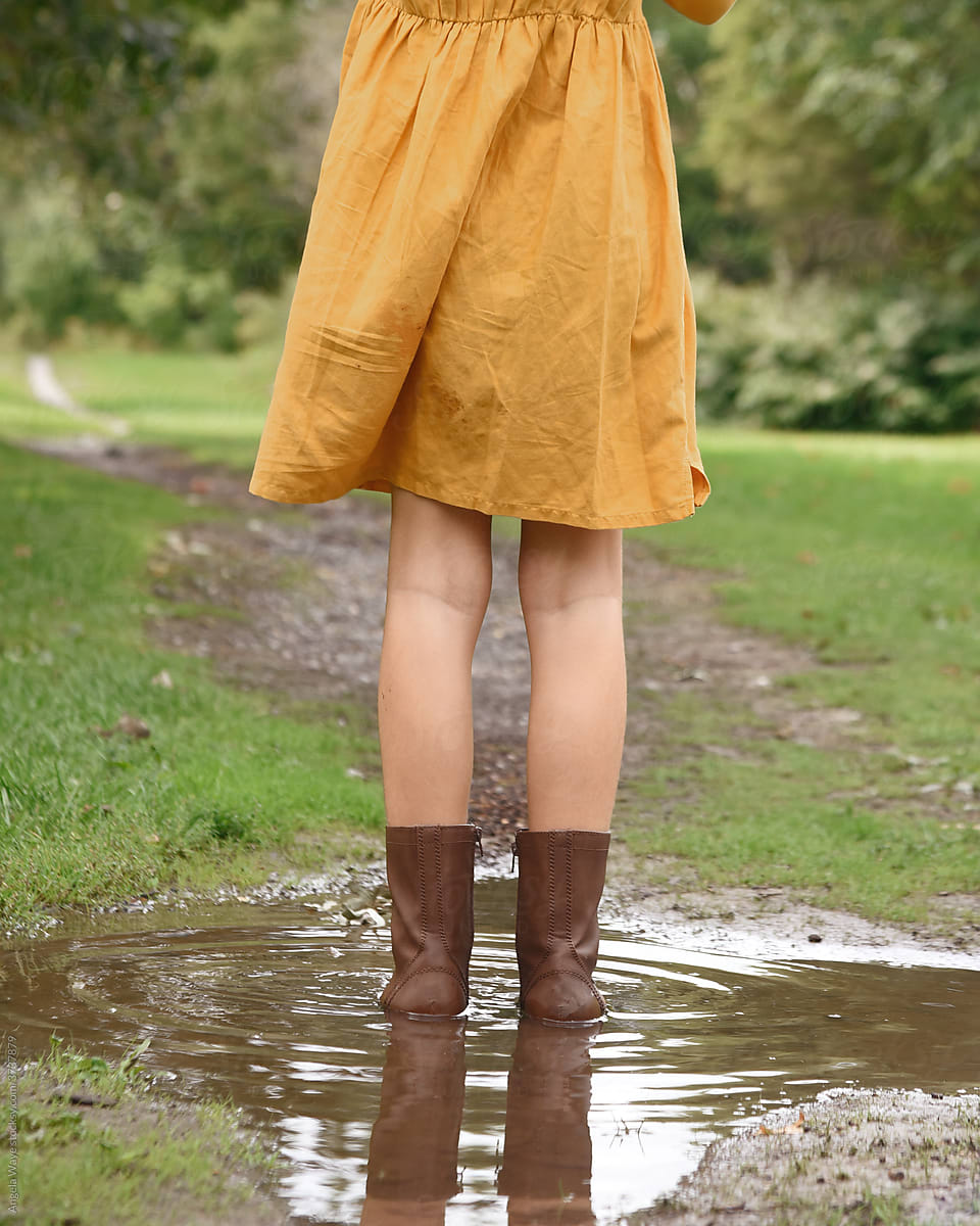 Child Standing in Mud Puddle Outside