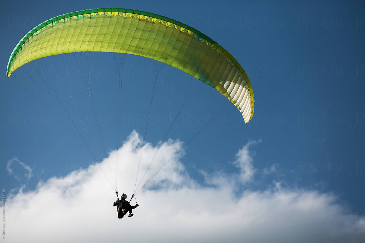 Unrecognizable person paragliding in blue sky