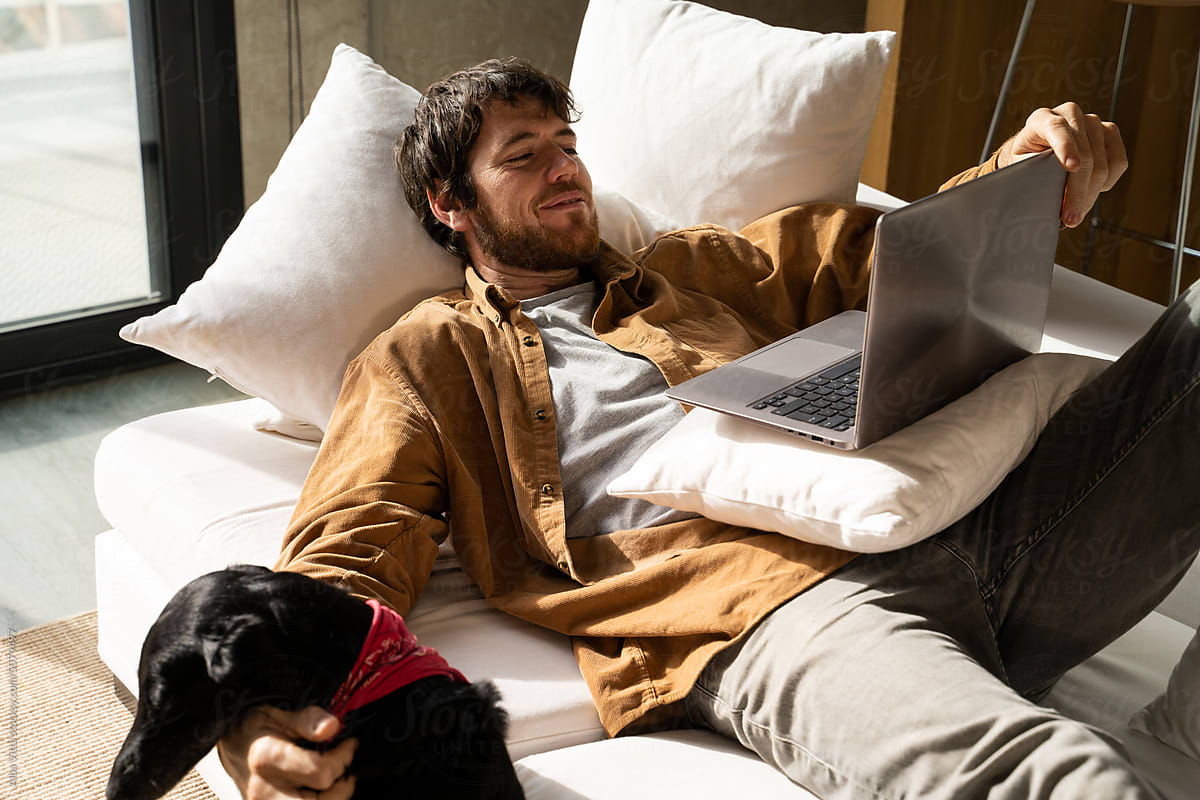 Man and dog watching movie on laptop at home