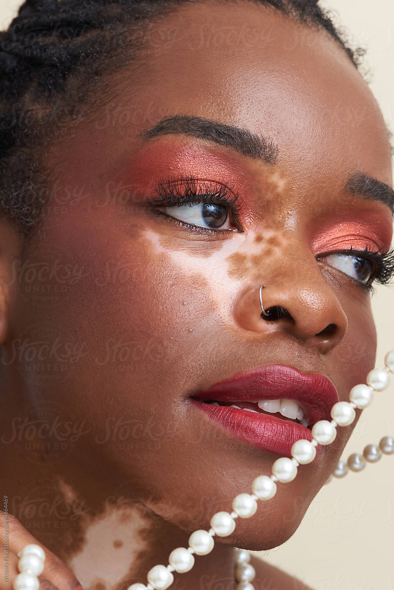 Close Up Image of Young Black Woman Holding Pearls with Red Lipstick
