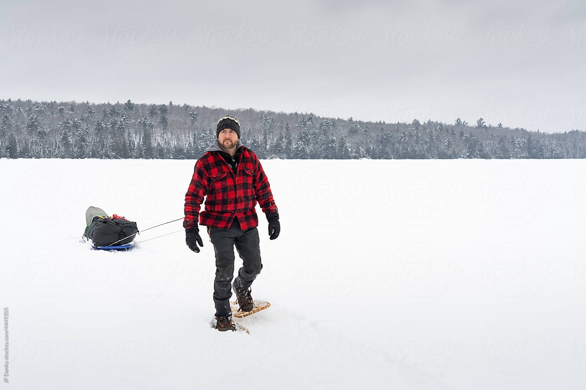 Traditional Snowshoeing with Winter Camping Sled on Frozen Lake