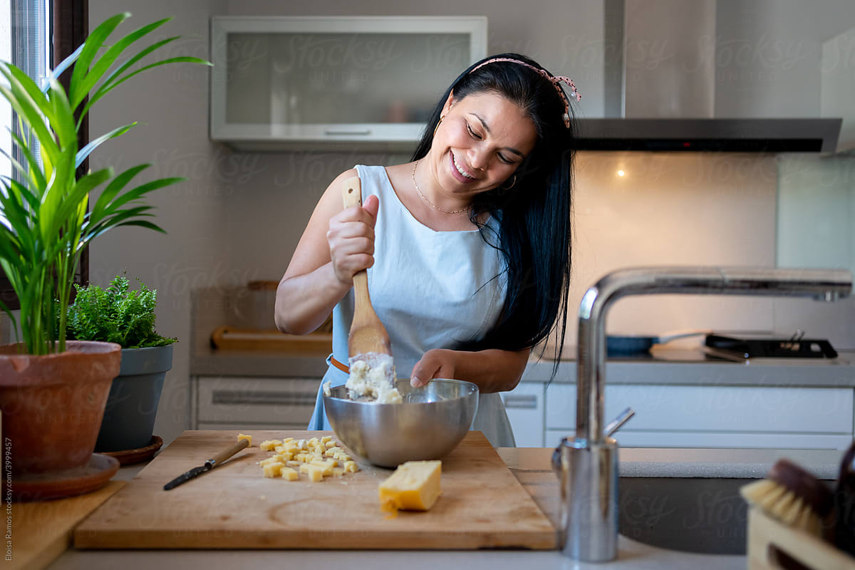 Pretty latin woman cooking mixing ingredients at home