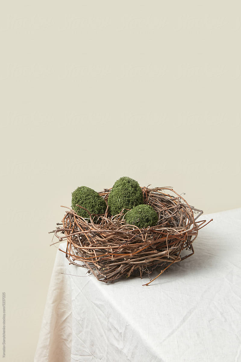 Crafted green mossy Easter eggs in woven nest.