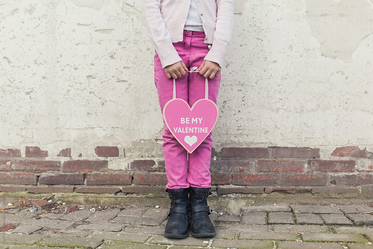 The body of a little girl holding a big pink Valentine heart