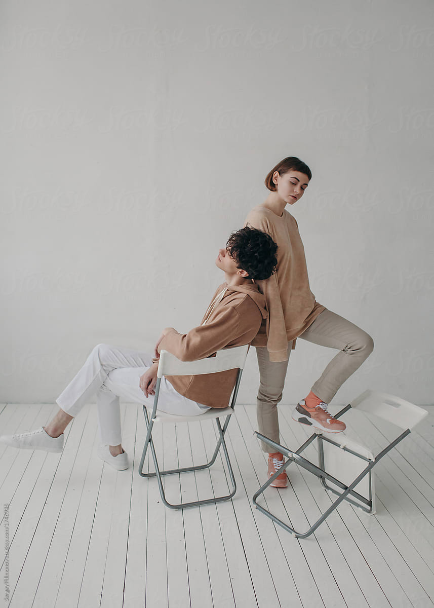 Couple posing with white chairs in minimalistic interior