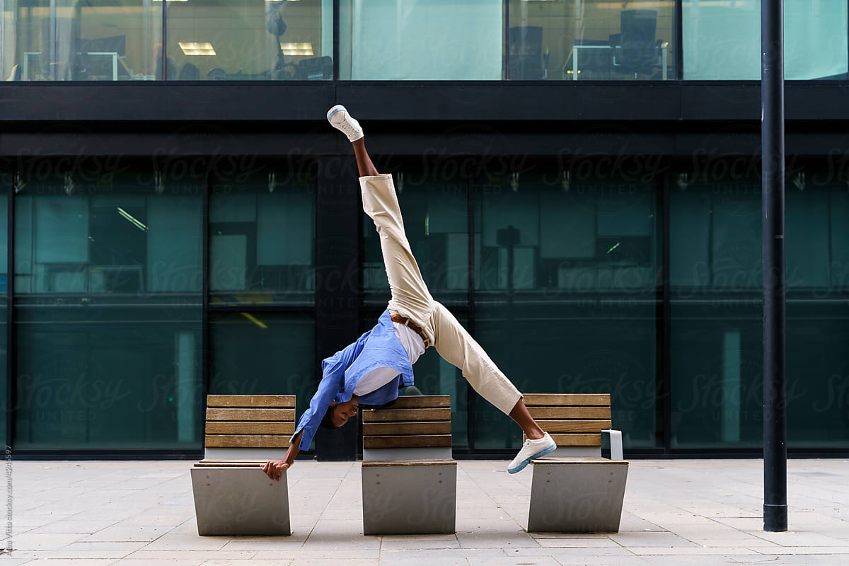 Stylish man doing yoga pose on bench