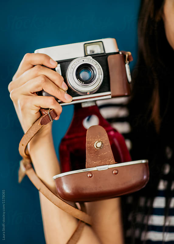Detail of latin woman hand holding an old film camera with leather stripe