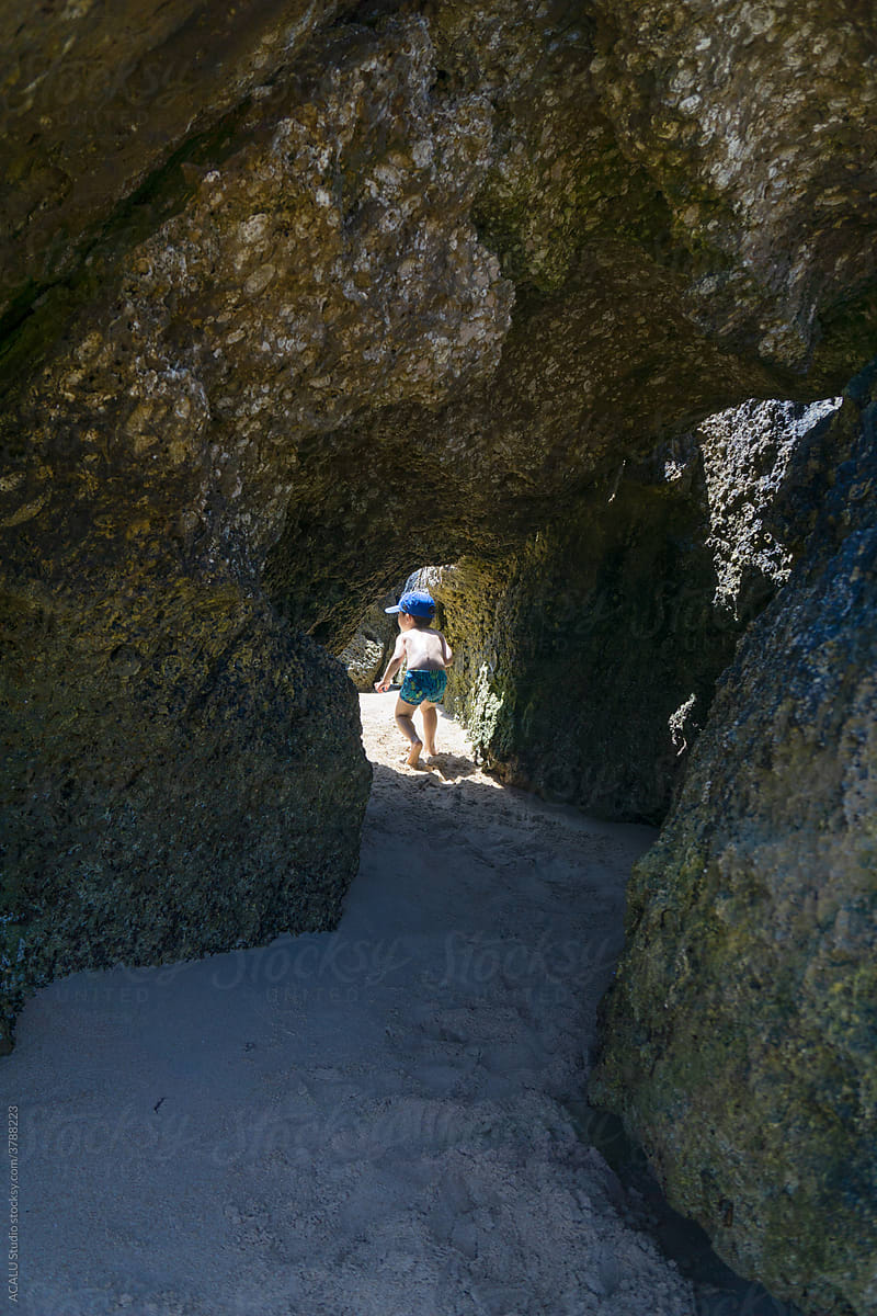 Curious kid going into a little cave on the beach