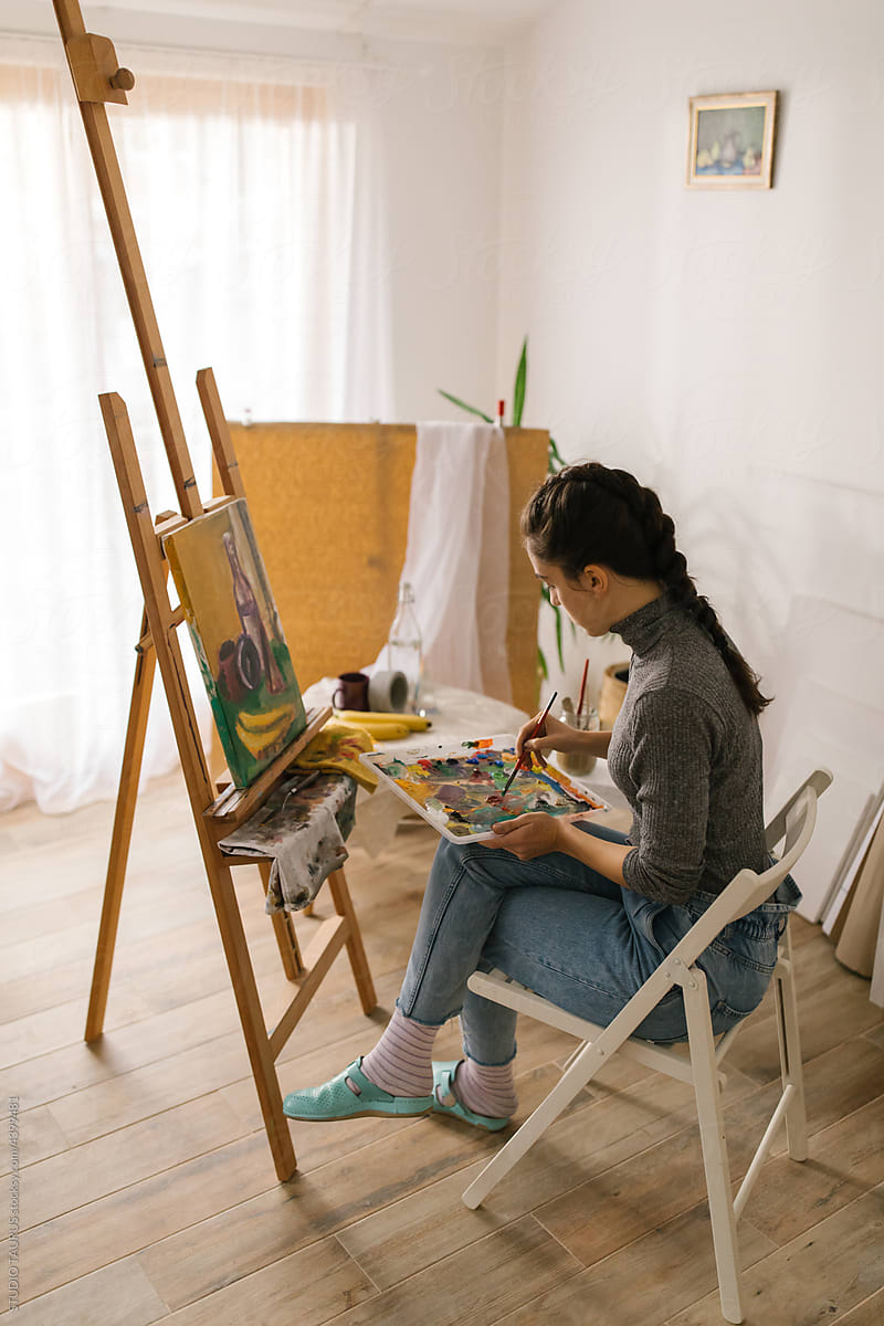 Artist sitting and painting on canvas in the studio