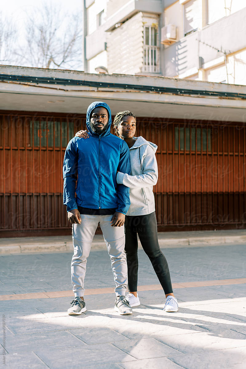 Sporty couple in warm activewear standing on street