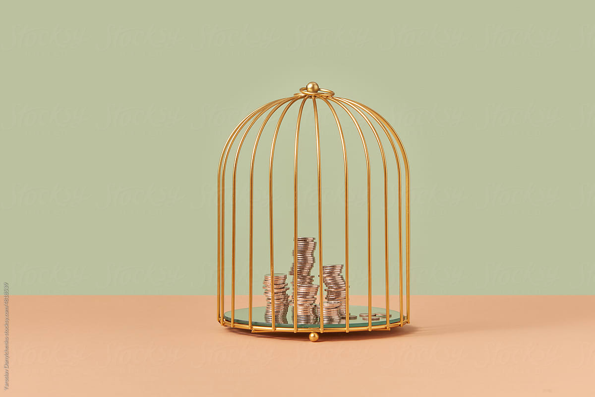 Golden birdcage with stacks of coins inside.